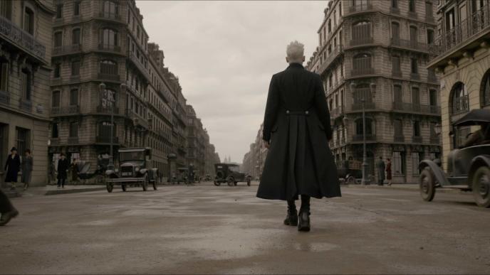 back shot of gellert grindelwald walking through 1920s paris