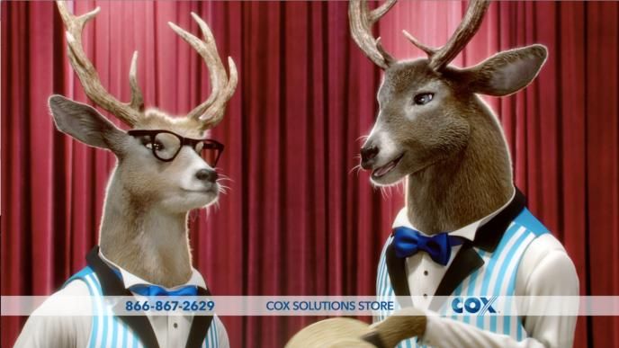 two cg animated reindeer bucks speaking with each other in front of a red curtain stage