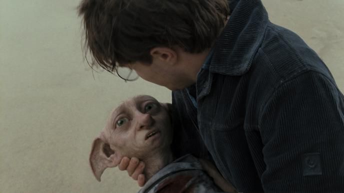 actor daniel radcliffe holding dobby the house elf in his arms while looking at him