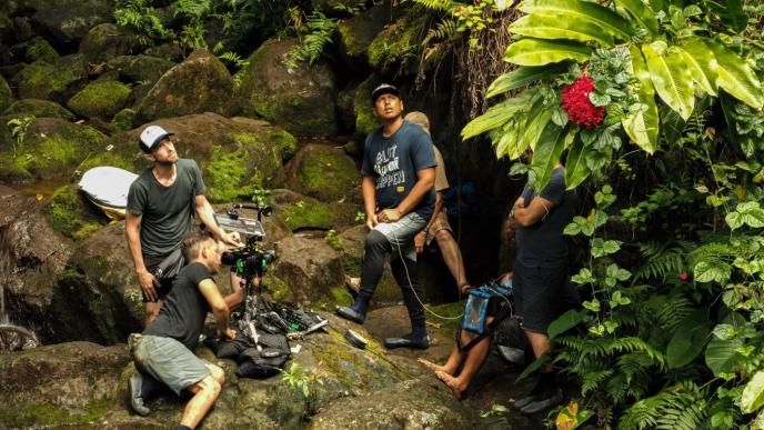 a film crew setting up gear in hawaiian forest