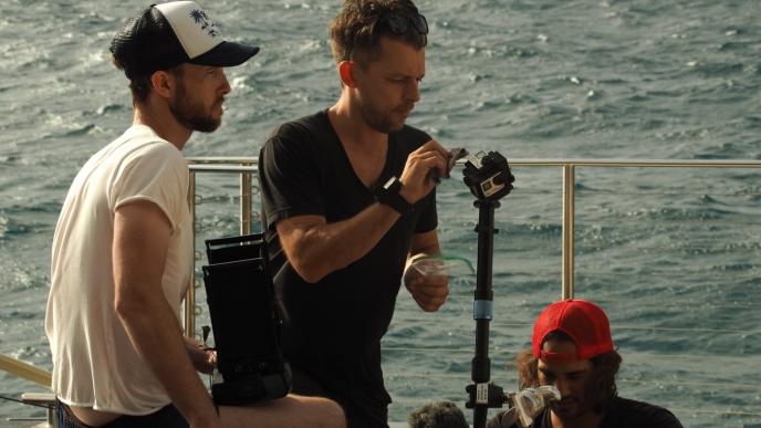 a film crew setting up gear on a yacht on the sea