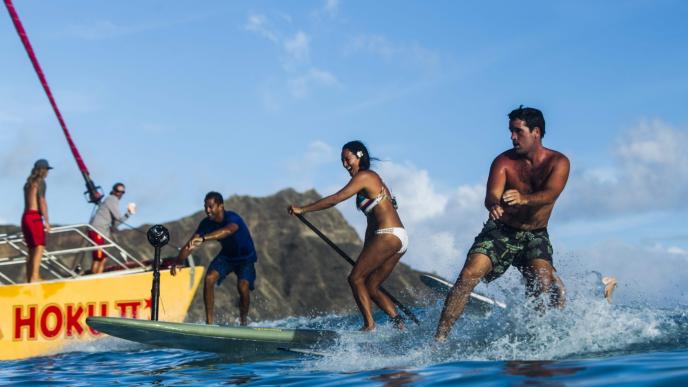 people surfing next to a yacht