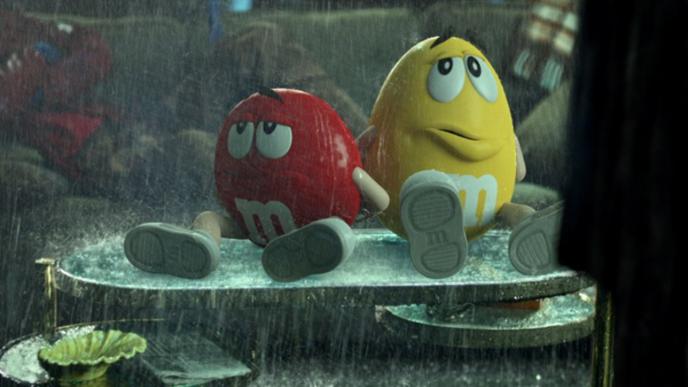 red and yellow m&ms sitting on a coffee table as rain pours down on them