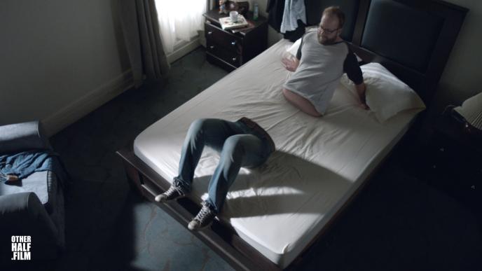 a man looking at his legs that are separate from his body on the edge of the bed