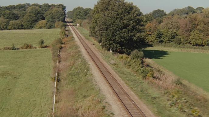 train tracks surrounded by green fields