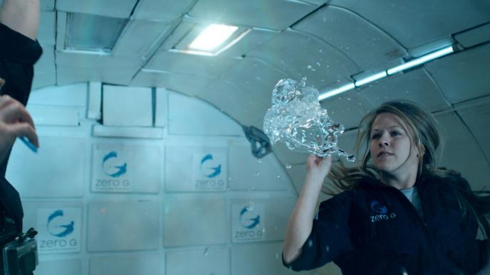 two astronauts in zero gravity as water floats amongst them