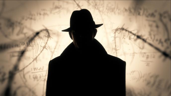 silhoutte of a man wearing a fedora facing the camera as mathematics equations and barbed wire are juxtaposed in the background