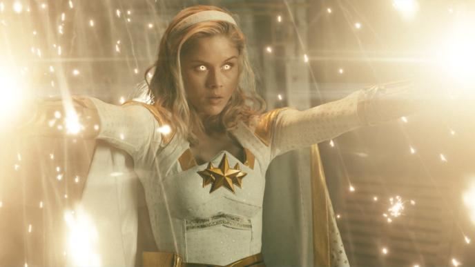 actor erin moriarty as annie january character holding arms up with whitened eyes as light surrounds her