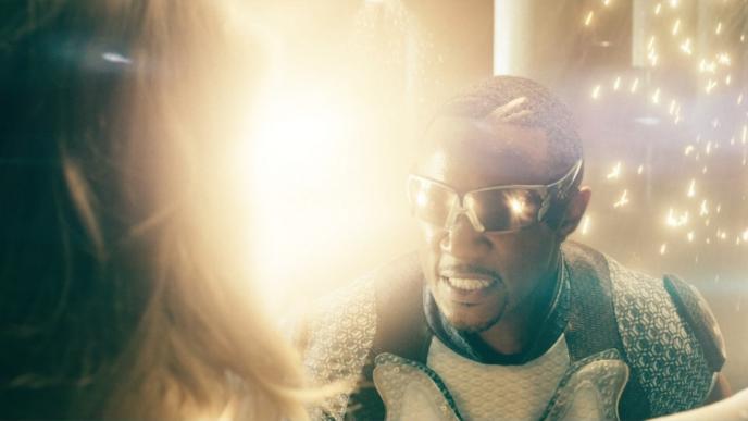 actor laz alonso as character mother's milk looking at actress erin moriarty as character annie january. sparks surround them