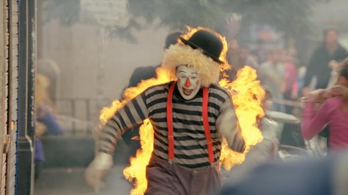 a clown in flames running while screaming