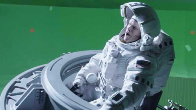 actor matt damon as character matt watney in an astronaut space suit sitting inside of a space shuttle in front of a green screen