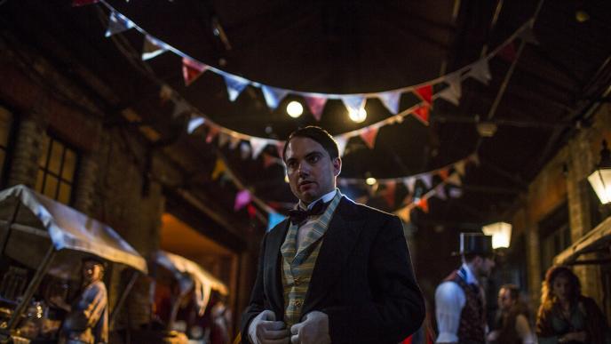 a victorian man standing in front of a film set in a victorian era street
