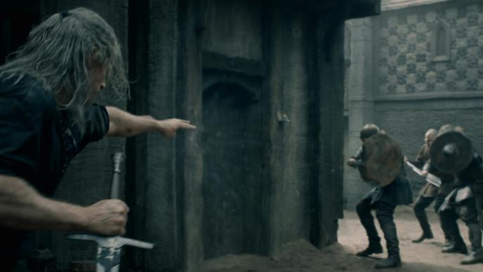 henry cavill as the witcher holding a sword while fighting off people holding shields