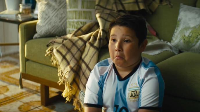 a child watching television at the foot of a sofa with a surprised impressed looked on his face
