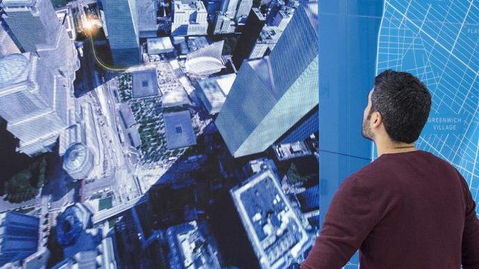 back view of a man looking up at a screen that covers a wall. the screen has information of the ford mobility world