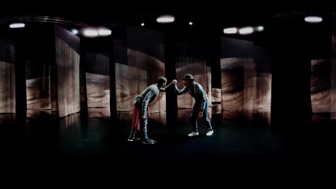 two dancers holding hands in front of an exhibition that has full length sheer sheets hanging from the ceiling