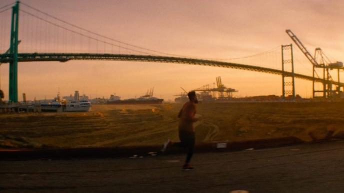 a person jogging by the brooklyn bridge. water is obsolete and ships are sitting on the ground