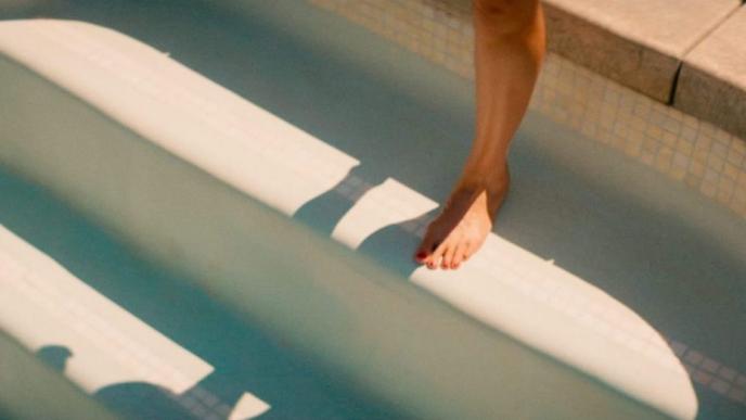 a leg stepping into an empty swimming pool