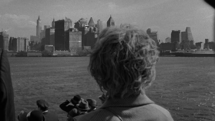 back view of a person on a boat looking at the new york city skyline from the sea