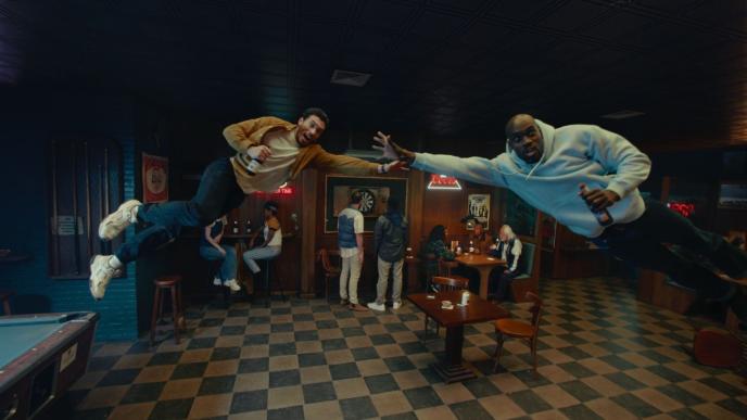 Two men leap up and sideways in a bar, as if to block a soccer goal