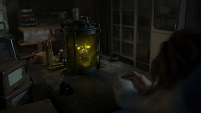 A skull in a jar, it's eye sockets are illuminated and it is surrounded by glowing algae