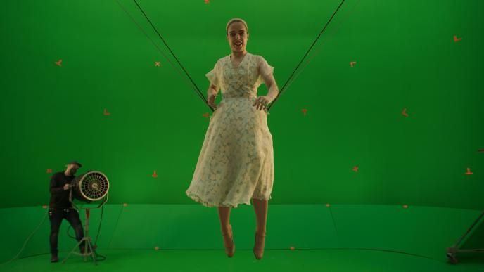 An actress, suspended in a harness, in front of a green motion-capture screen