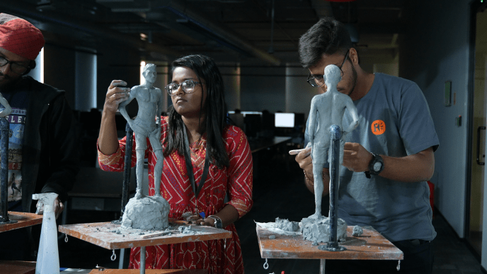 Three artists take part in a sculpting class, creating small human sculptures