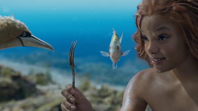 Halle Bailey as Ariel, holds a fork up to Scuttle and Flounder