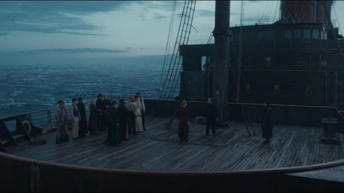 The cast of 1899 stand on the deck of the ship, with the ocean in the background