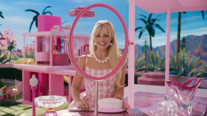 A still from Barbie showing Margot Robbie looking into a fake mirror in the Barbie dreamhouse.