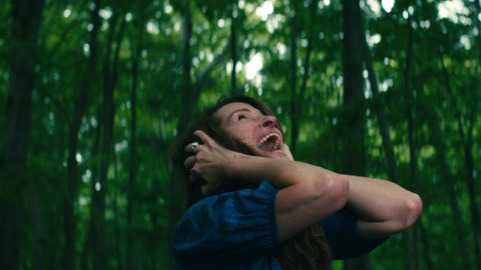 Julia Roberts in Netflix's film "Leave the World Behind". She stands in a green woodland with her hands over her ears, screaming