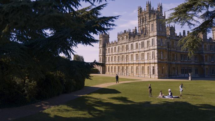 An exterior shot of Downton Abbey, with people sitting outside on the lawns