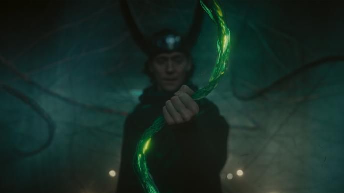 Loki grabs a strand of time, glowing in green