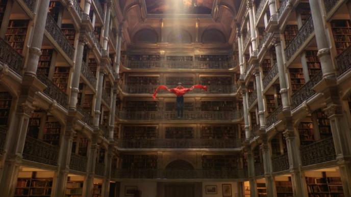 A boy floating down from the ceiling of a large columned room. There is light spilling from a hole in the ceiling.