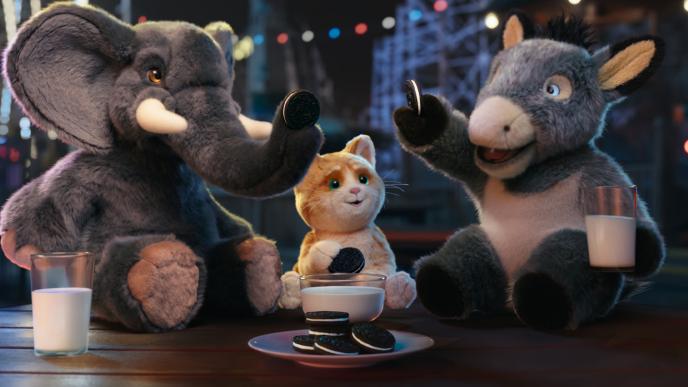 Three stuffed toy animals, an elephant, a cat, and a donkey are cheering with Oreos over glasses of milk.