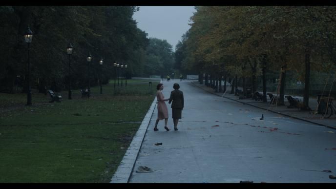 Two women walking down a wide park path