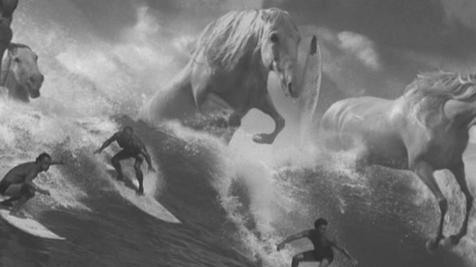 Surfers ride a large wave while giant horses gallop through the wave as well