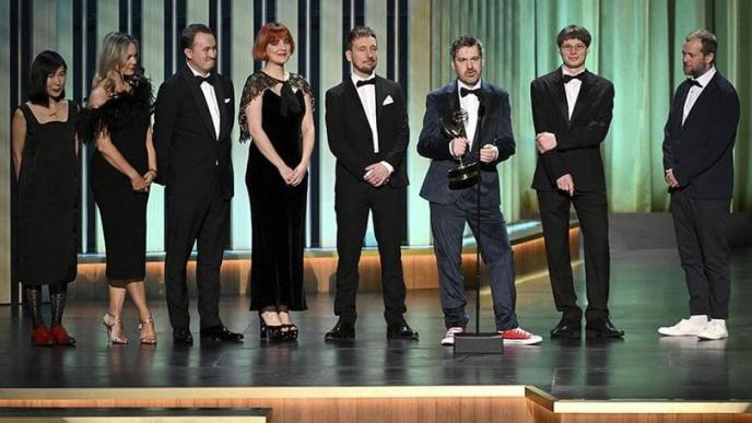 A group of men and women on a stage wearing black tie accepting an awards.