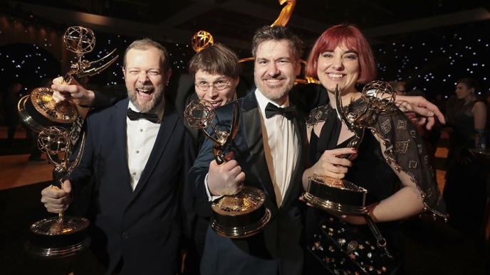 Four people holding awards in black tie celebrating.