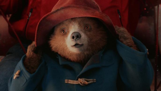 Paddington the bear wearing a red rain hat and blue coat