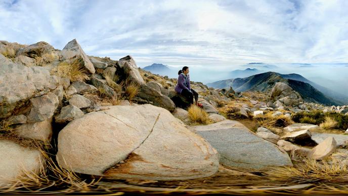 Lady sitting on rocks looking out to the distance