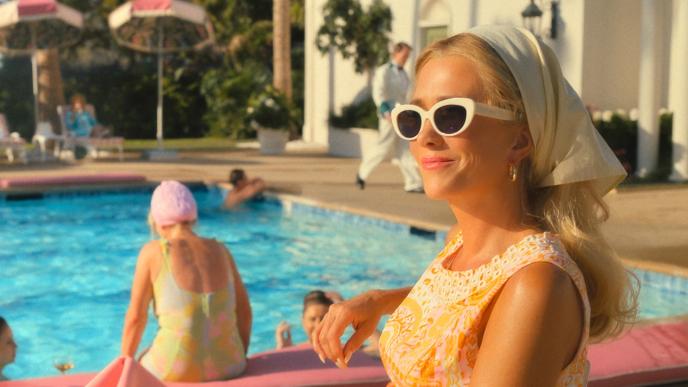 Kristen Wiig sits poolside in a 1960s holiday resort setting