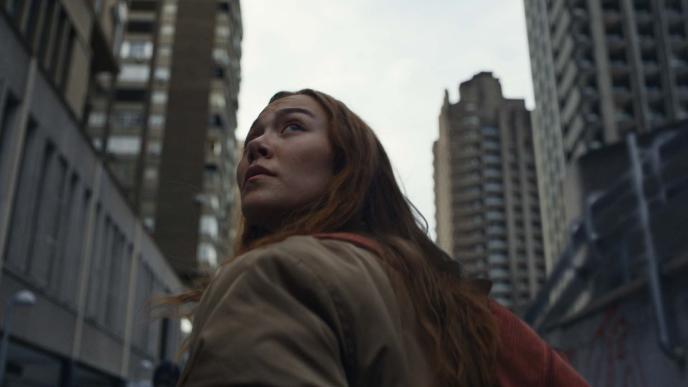 Woman walking around a city, looking up at skyscrapers