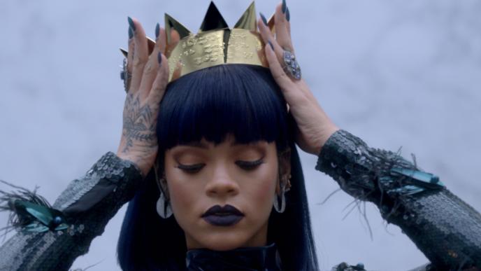 Rihanna puts a crown on her head and looks down