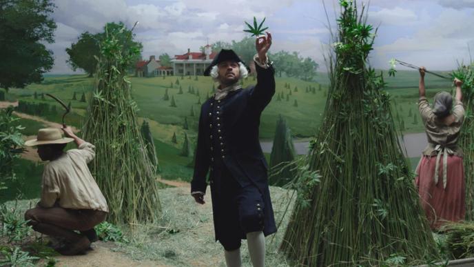 a coloniser holding up a cannabis leaf as farmers are working