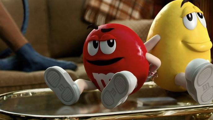 The red and yellow M&M mascots sit back to back with their hands tied