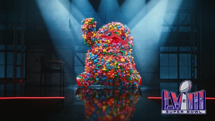 A giant red gummy Monster covered in Nerds dances on stage, there is the Super Bowl LVIII logo in the bottom left corner.