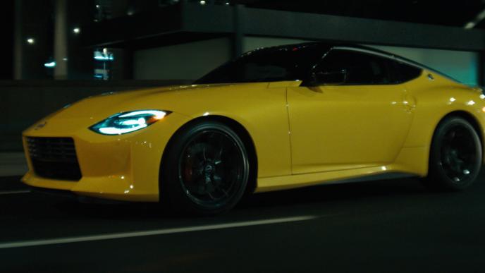 A yellow Nissan Z drives in the night
