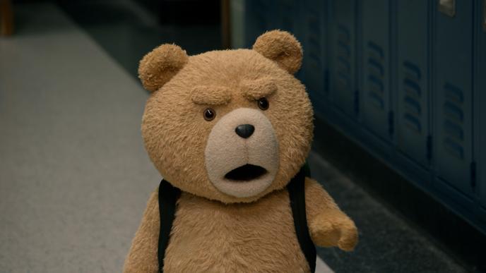 Ted stands in a school hallway, wearing a backpack, looking angry