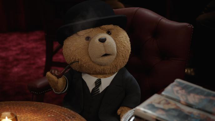 Ted sits in a leather chair, wearing a full suit and bowler hat, holding an old fashioned smoking pipe
